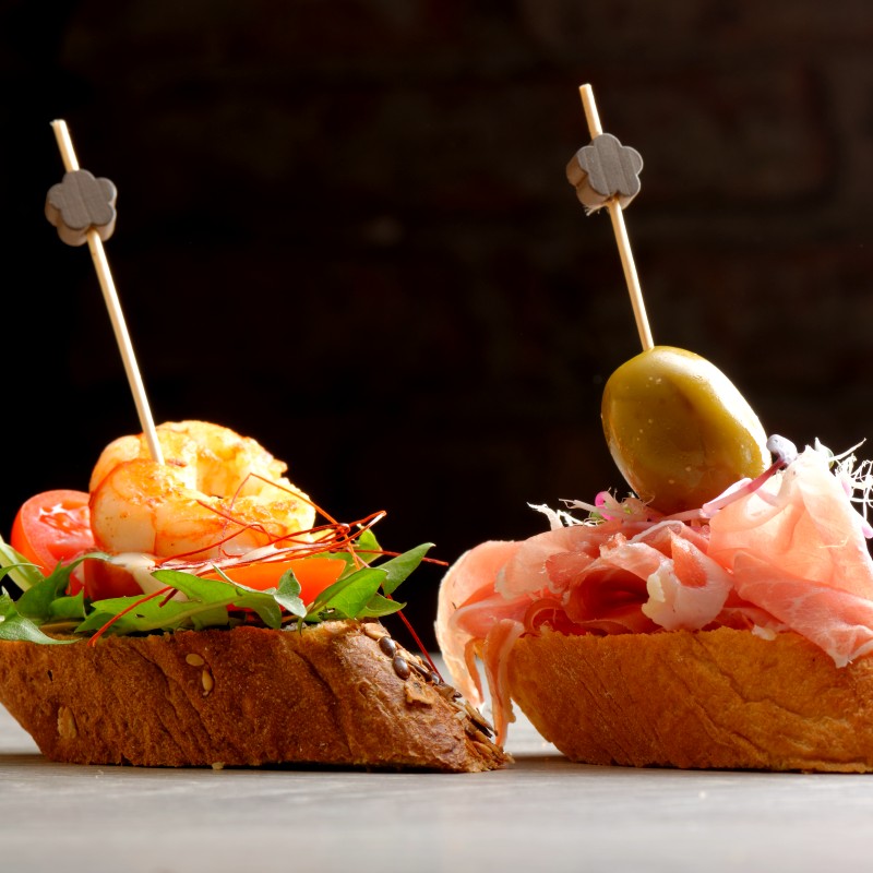 Tapas on crusty bread selection of spanish tapas served on a sliced baguette.